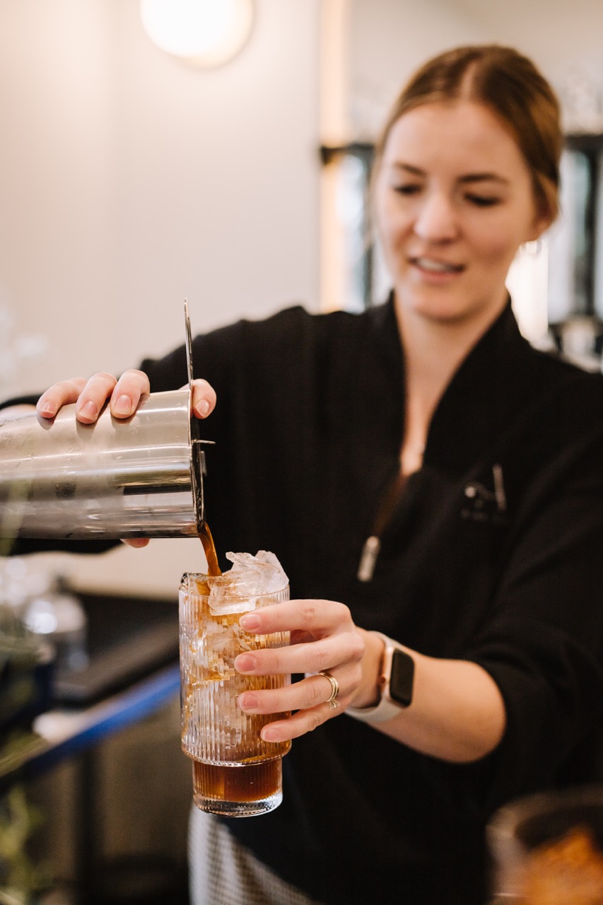 Bartender mixing a drink in a brightly lit luxury bar.