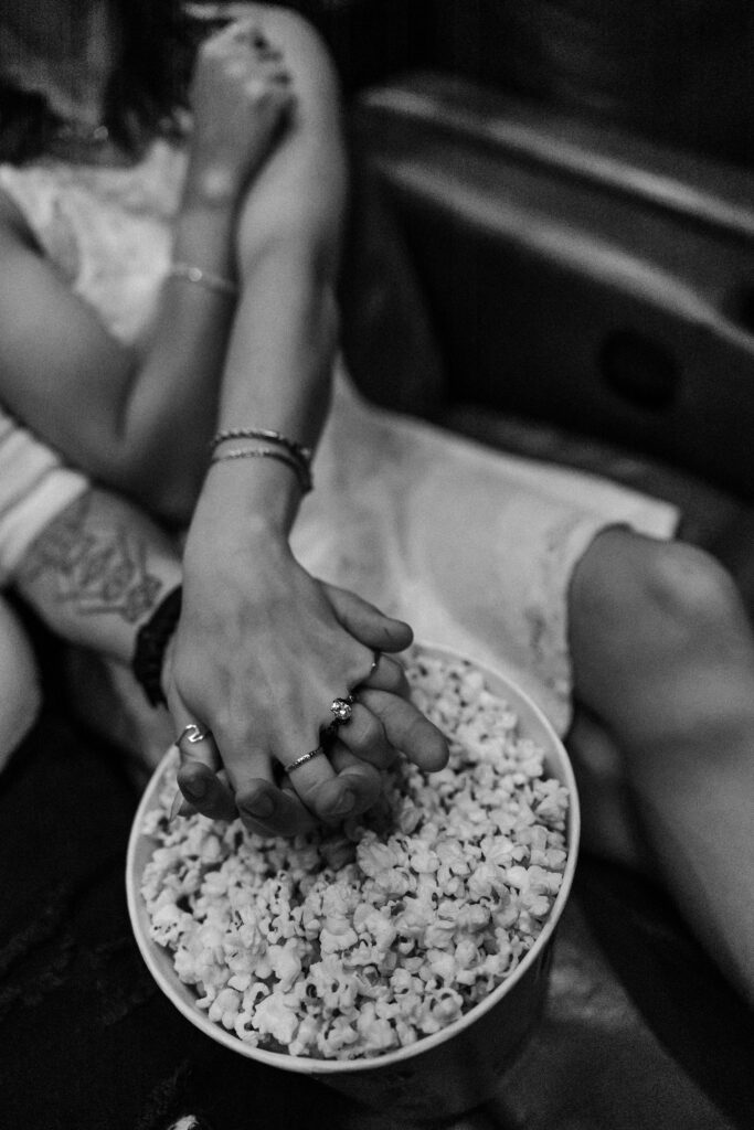 Man and women reaching into a bucket of popcorn. 