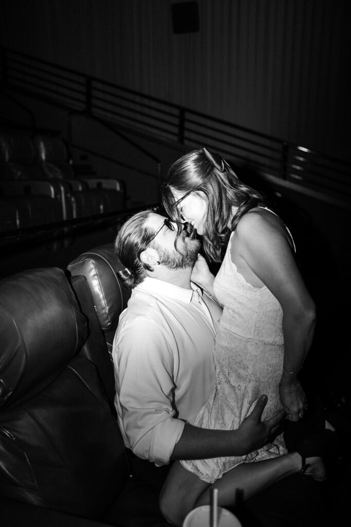 man and women sharing a kiss in a movie theater. 